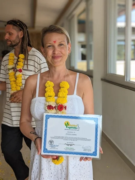 Graduates holding their yoga certifications after completing YTTC