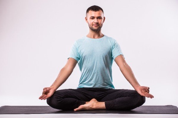 Man sitting cross-legged on a yoga mat in a meditation pose