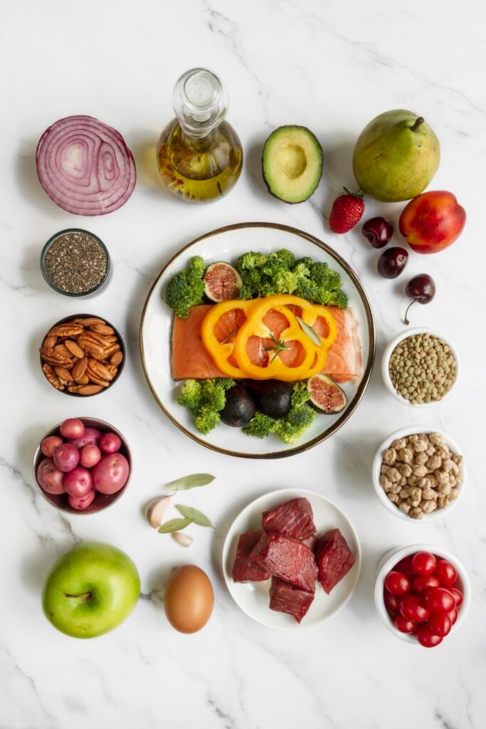 Healthy Flexitarian Diet Food Arrangement With Fresh Vegetables, Fruits, Nuts, Seeds, Salmon, And Lean Meat on a White Marble Background