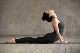 Woman practicing Bhujangasana (Cobra Pose) yoga, lying on her stomach and lifting her upper body with her arms.