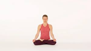 A Woman in a Red Tank Top and Dark Leggings Sitting in a Lotus Position.