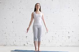 Woman standing on a yoga mat in Mountain Pose (Tadasana)