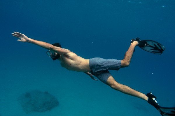 Man snorkeling underwater with fins and a diving mask